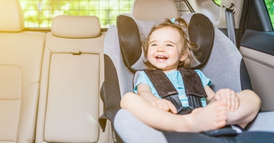 smiling child sitting in a front-facing car seat