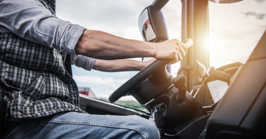 close up of a truck driver holding the steering wheel with both hands
