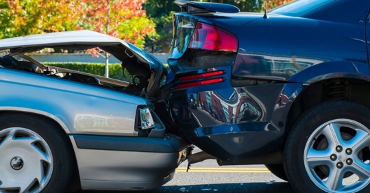 a grey car with smashed hood crashing into the back of a black car