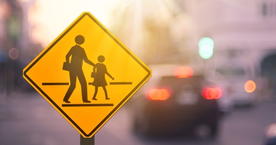School crossing sign with cars in the background