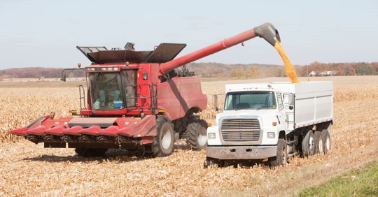 large truck in a field getting loaded up with grains