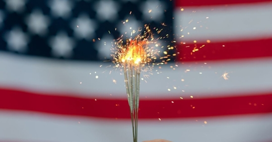 lit up sparklers with an american flag in the background