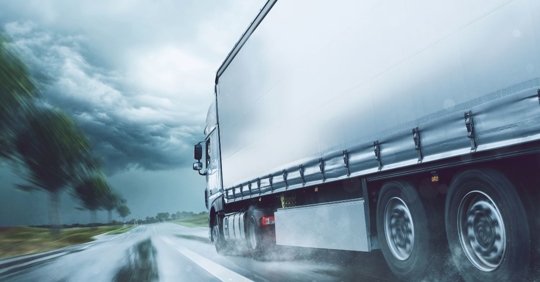 large truck driving towards a storm cloud on a rainy afternoon
