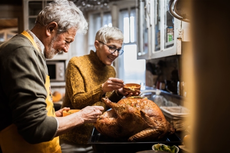older couple cooking Thanksgiving turkey